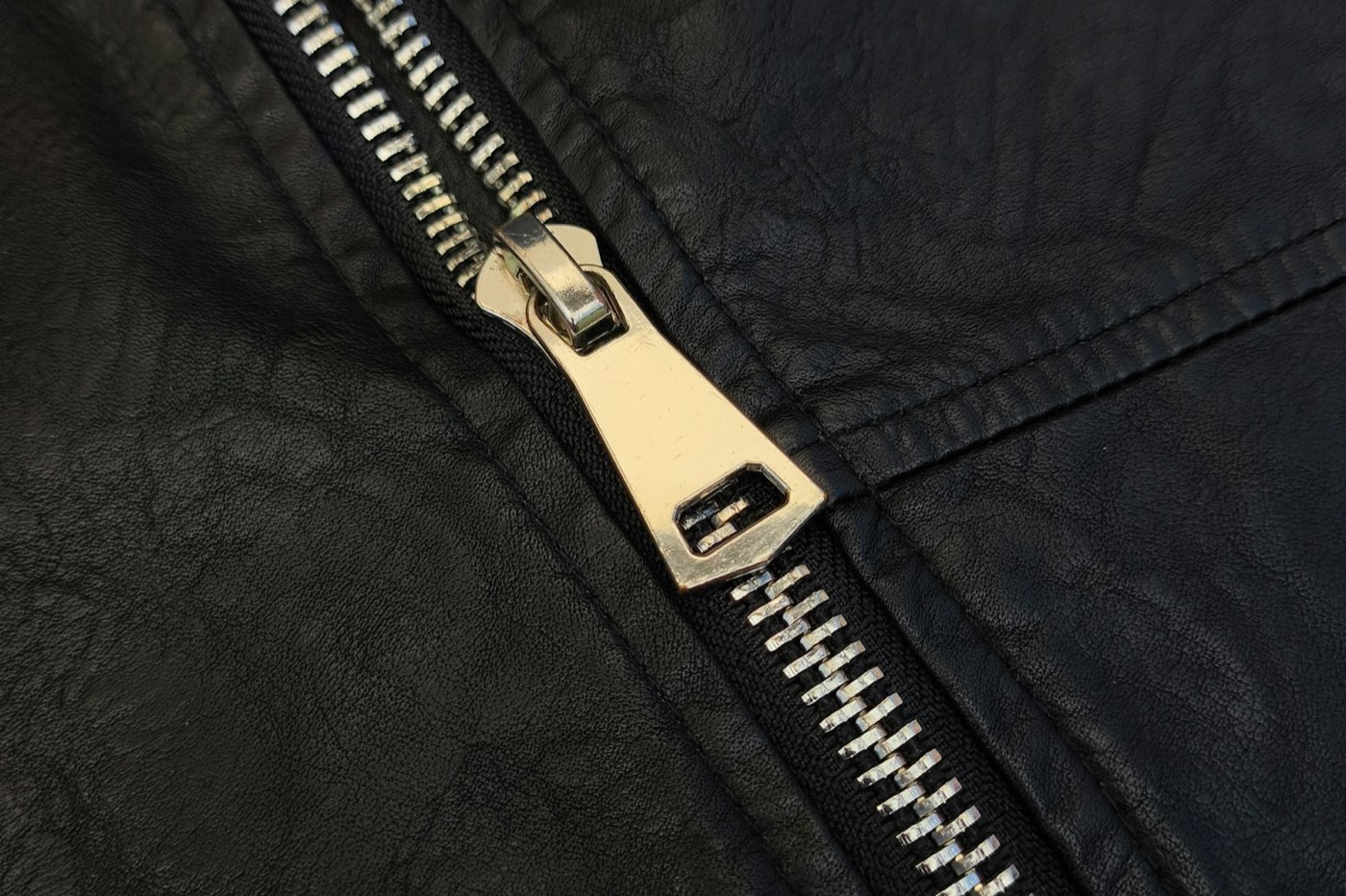 Close-up of a silver zipper on a black leather jacket