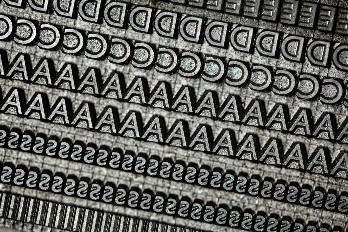 Rows of old metal letterpress type, letters and numbers lined up in a tray