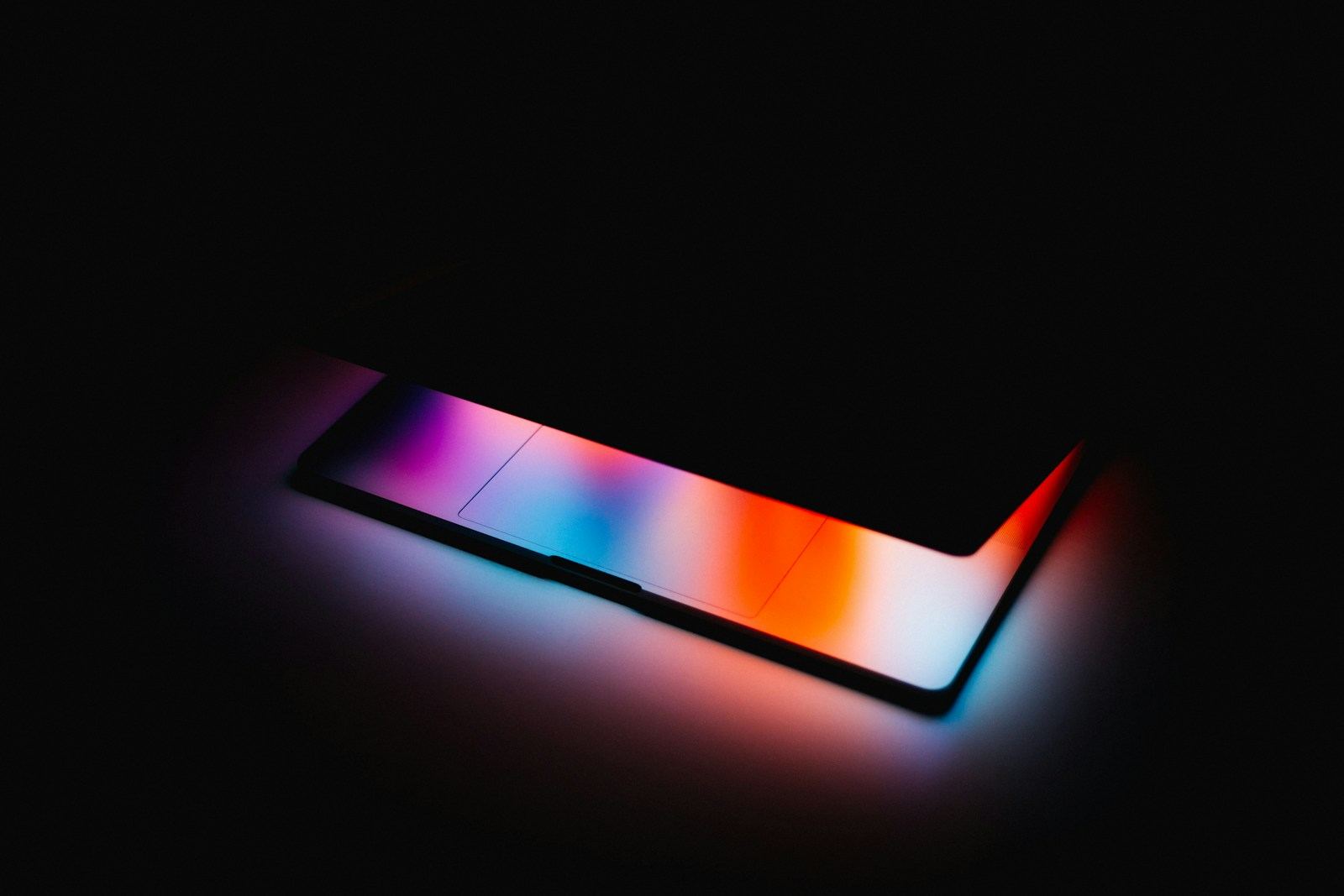 A phone lying on a dark surface, its screen casting a soft glow of color